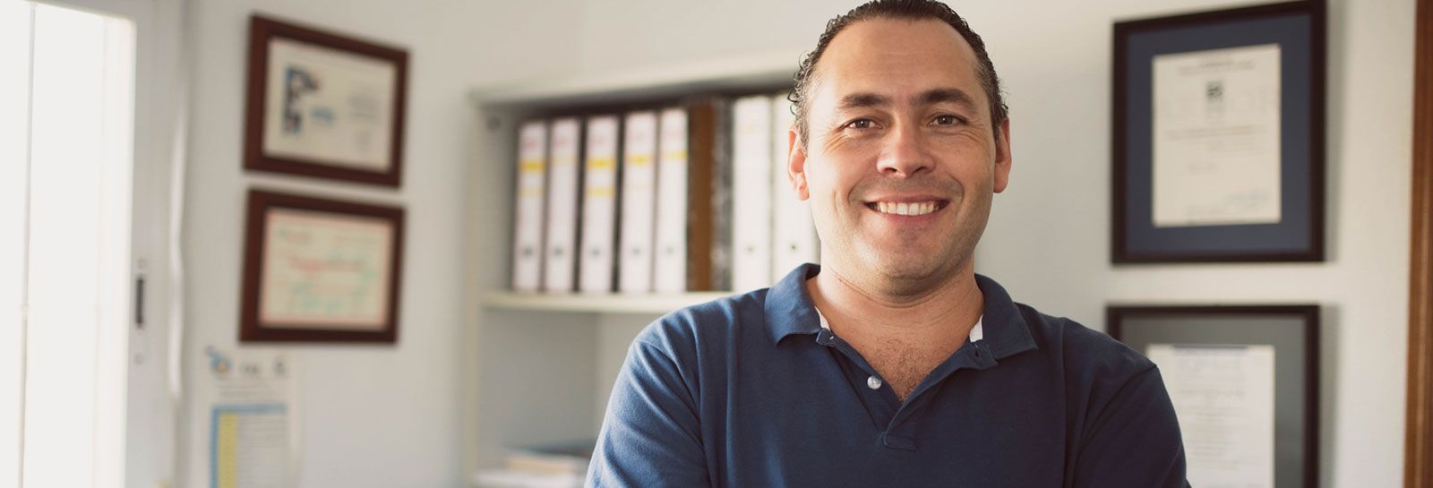 Smiling man stands in his office banner image